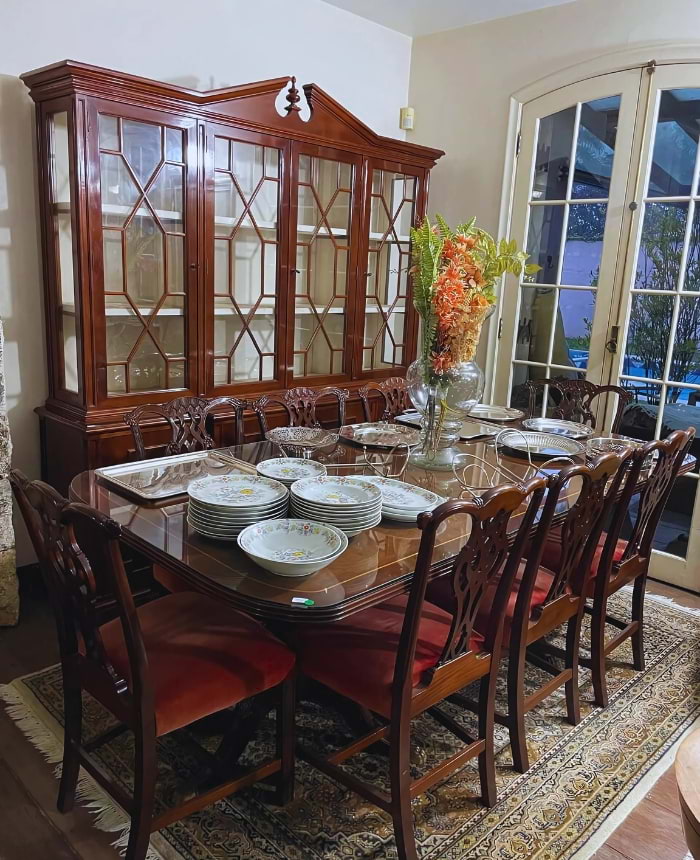 Mesa de jantar de jacarandá com oito cadeiras e cristaleira de vidro ao fundo